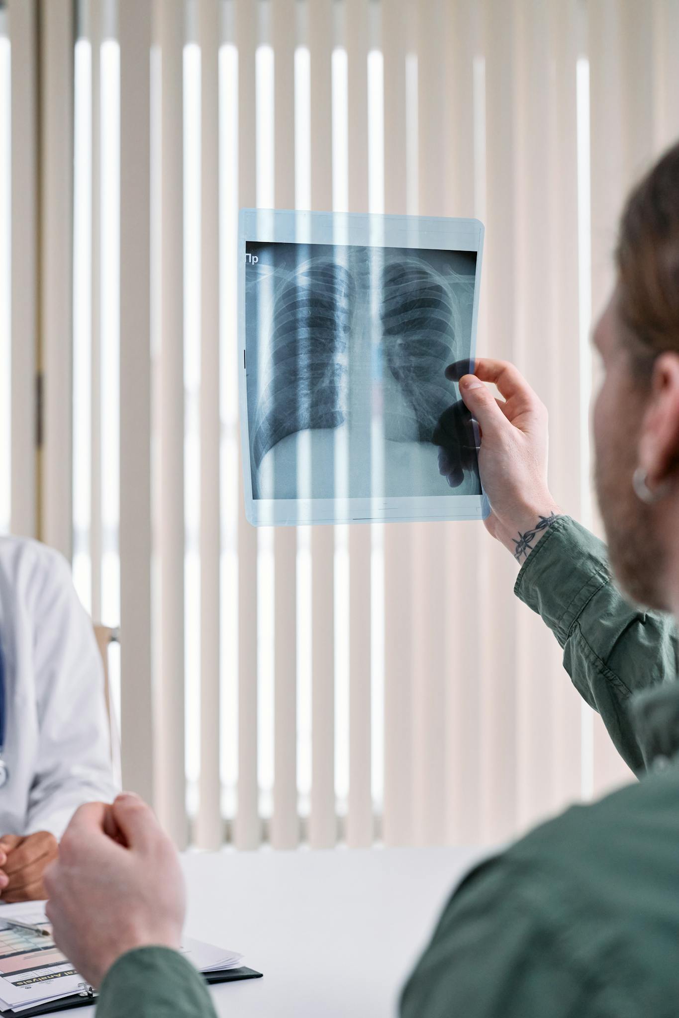 Medical professional examining an X-ray image of human lungs in a clinical setting.